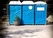 Blue portable toilets with hand wash station and exterior lighting at outdoor event