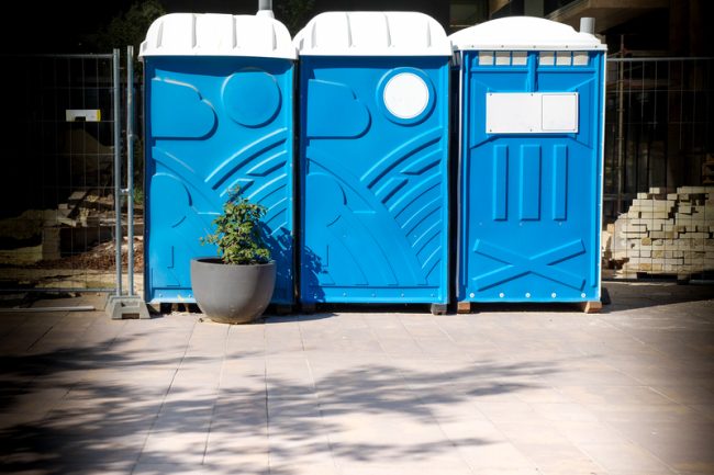 Blue portable toilets with hand wash station and exterior lighting at outdoor event
